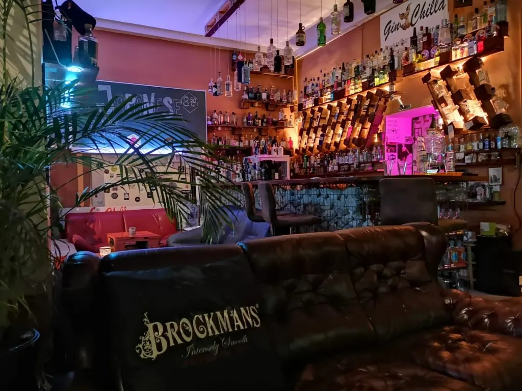 Lounge der Gin Chilla Bar mit rotem Sofa, Ledersesseln und beleuchteten Ginregalen